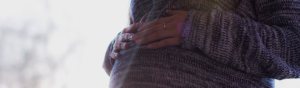 hands folded over pregnant belly