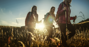 three young women hiking through a field